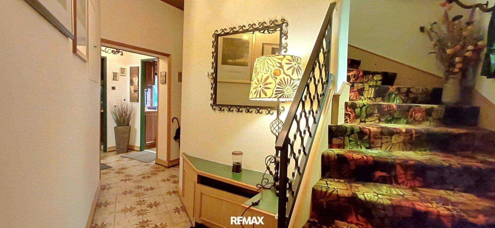 Flur mit gemustertem Teppich auf der Treppe und einem Spiegel an der Wand.