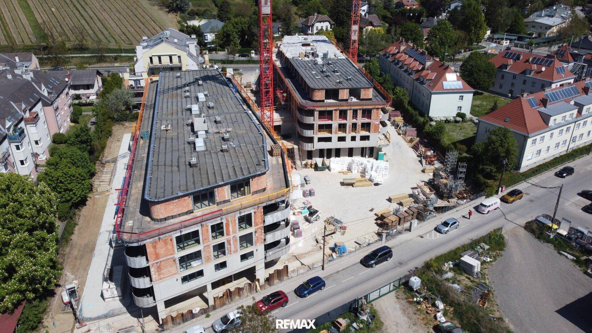 Übersicht der Baustelle mit zwei modernen Gebäuden im Rohbau und umliegender Bebauung.