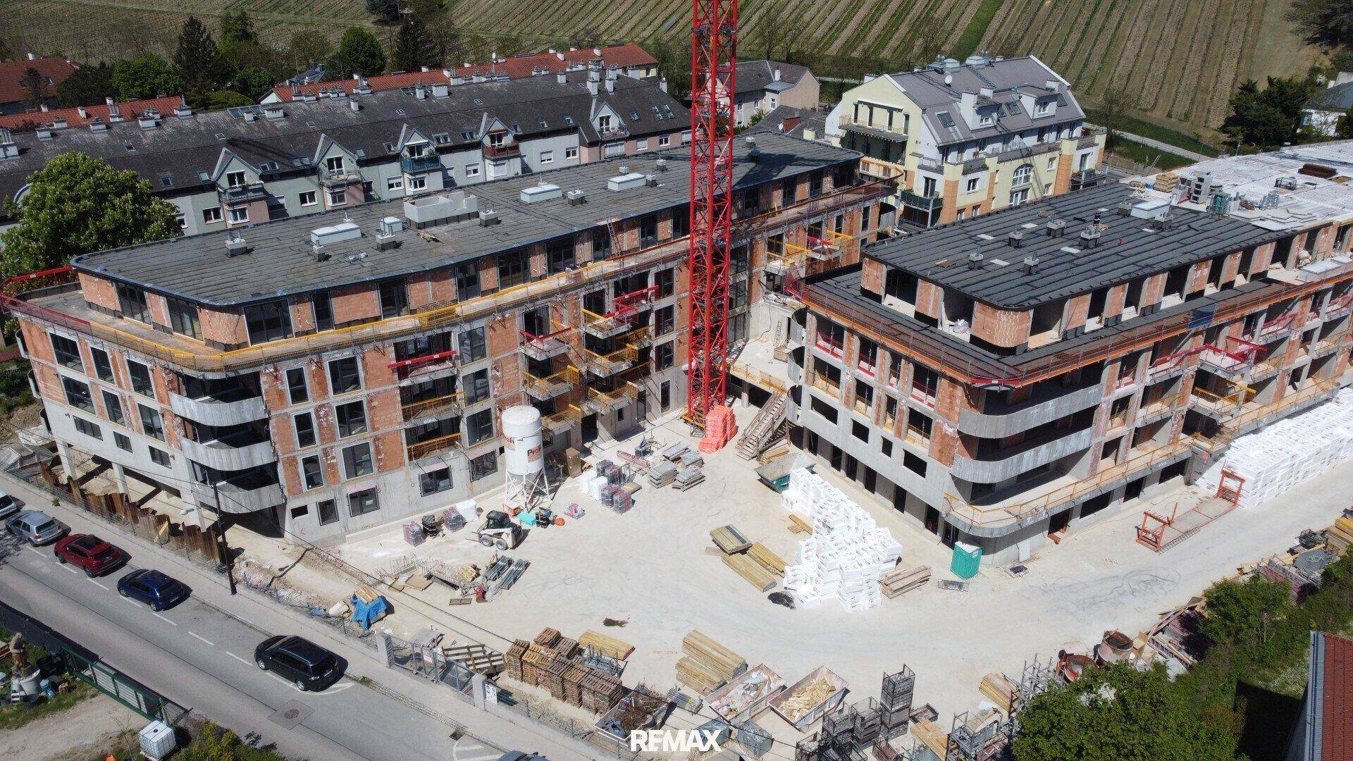 Luftaufnahme einer Baustelle mit zwei im Bau befindlichen Mehrfamilienhäusern und Kränen.