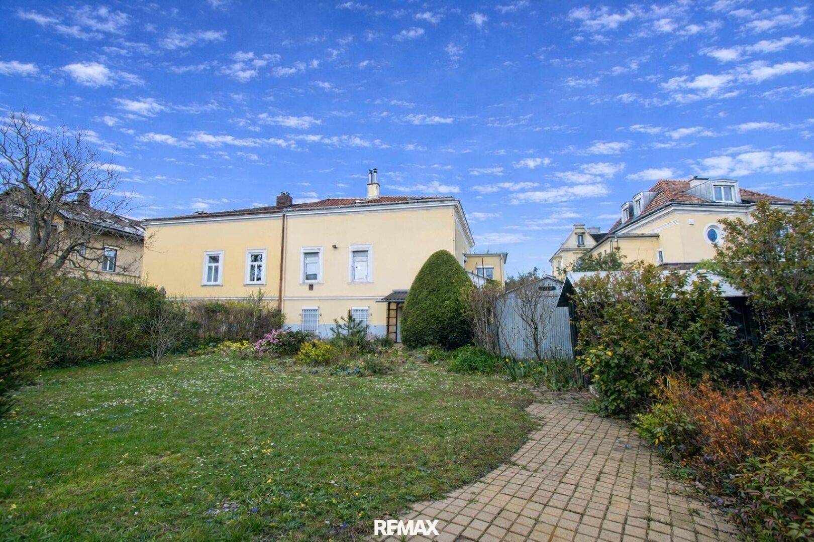 Großer Garten hinter dem Haus mit Rasenfläche, Bäumen und einem gepflasterten Gartenweg.