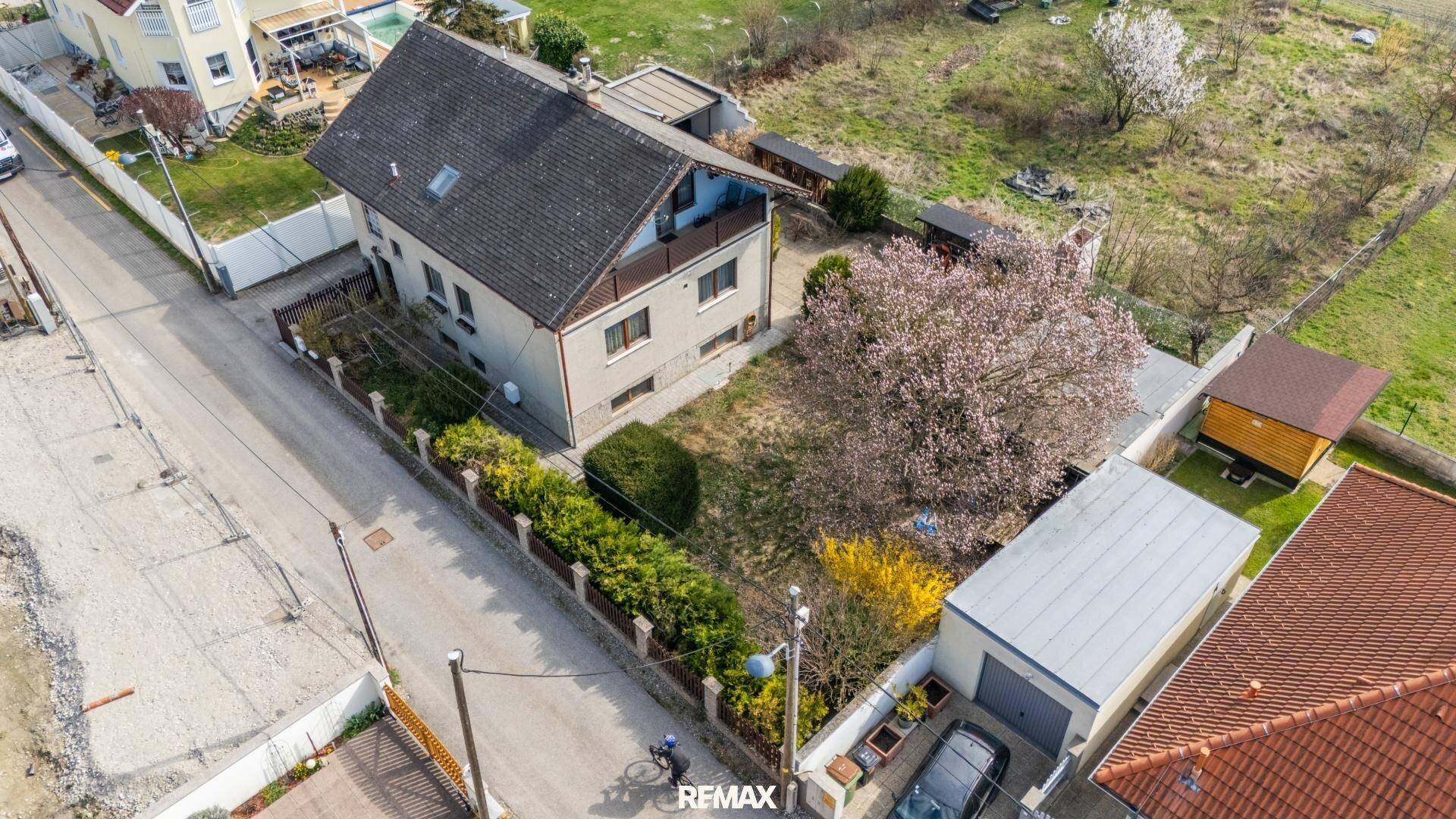 Gesamtansicht des Hauses von oben mit Grundstück, Straße und umliegender Bebauung.