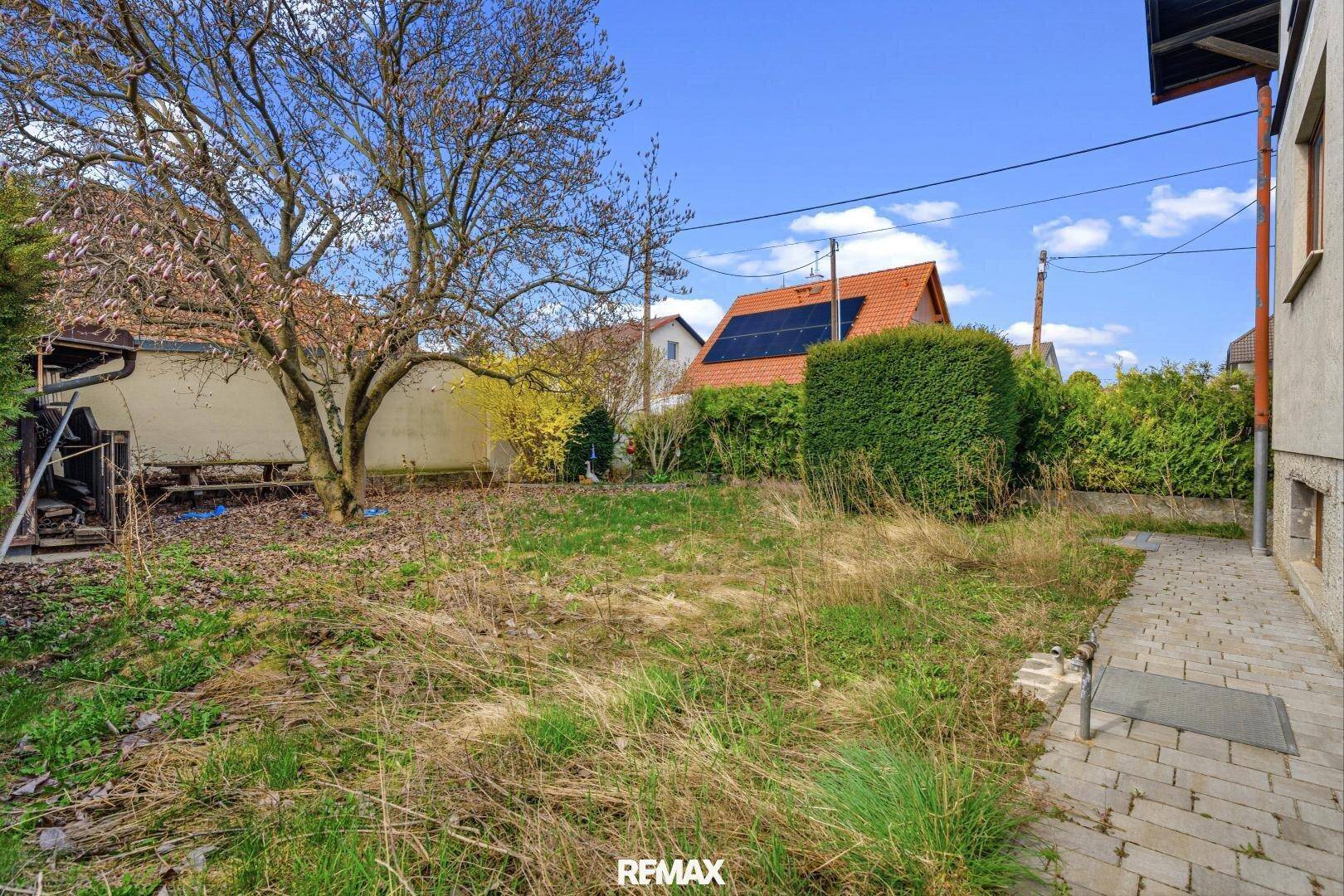 Großer Garten mit Rasenfläche, Bäumen und angrenzendem Haus.