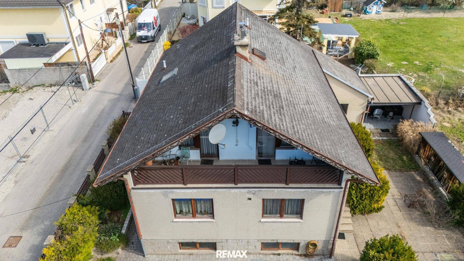 Rückansicht des Hauses mit großem Balkon im Obergeschoss und Blick auf die Umgebung.