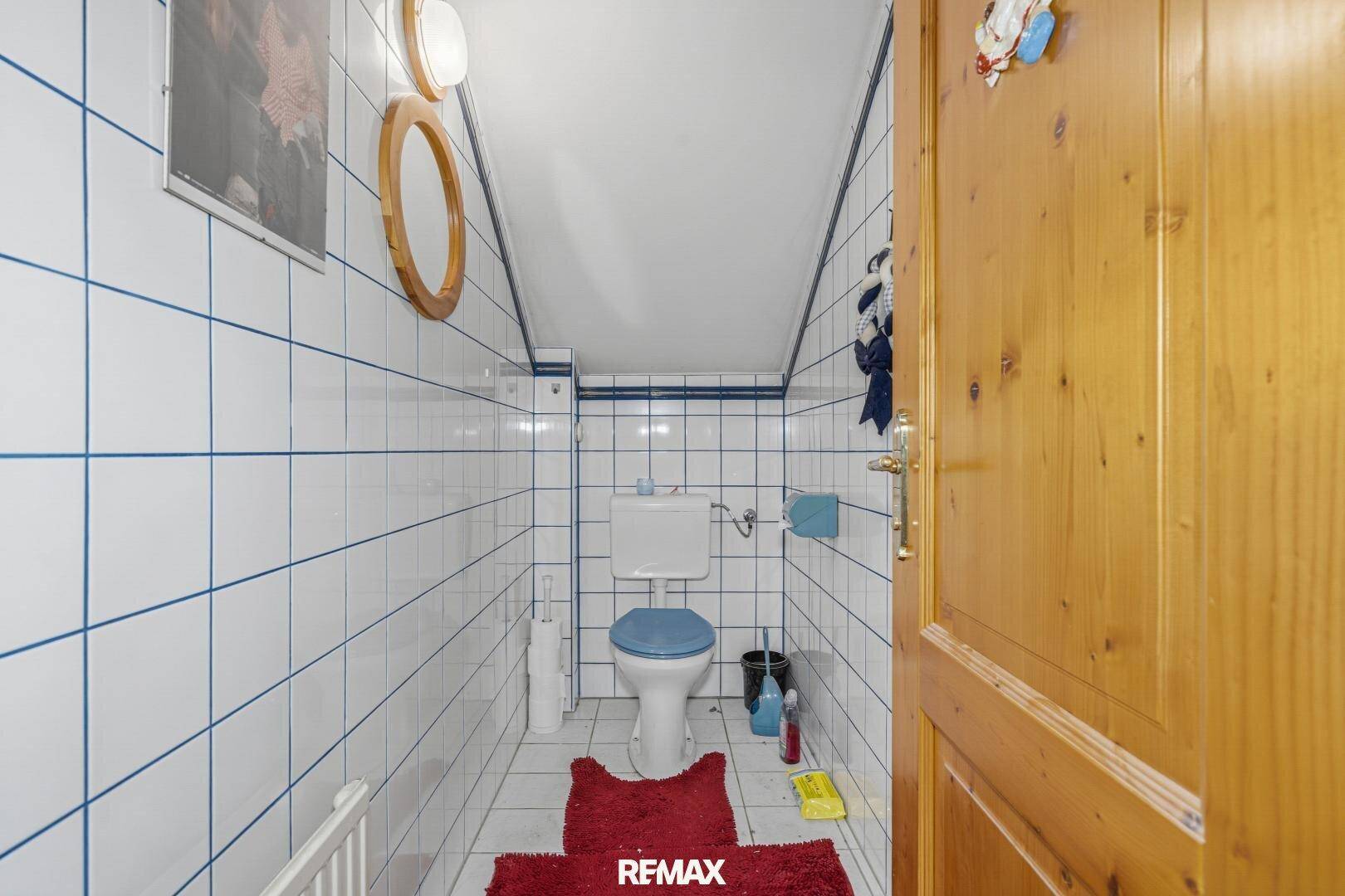 Kleines WC mit weißen Fliesen, blauen Akzenten und Toilette.