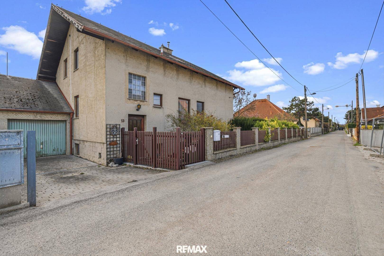 Ansicht des Hauses von der Straße mit Garage und Zaun.