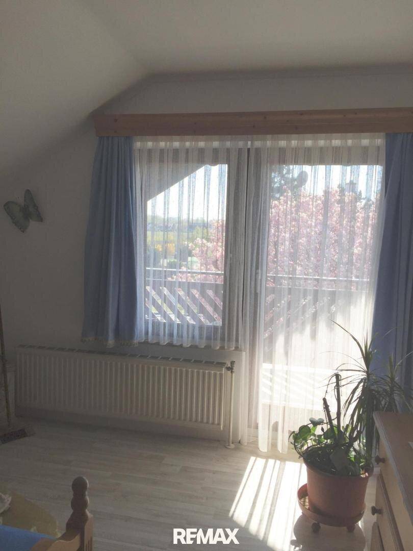 Helles Schlafzimmer mit großem Fenster, Heizkörper und Blick ins Freie.