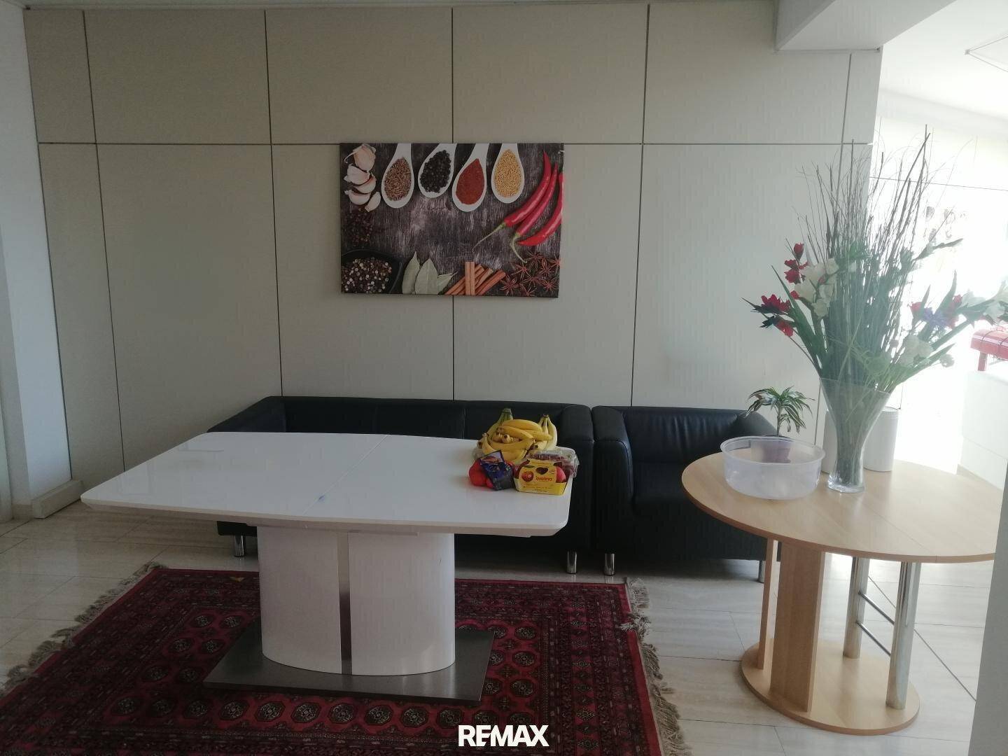 Wartebereich mit bequemen Ledersofas, einem modernen Tisch und dekorativen Elementen.