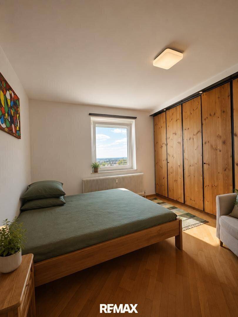 Gemütliches Schlafzimmer mit Holzbett, Einbauschränken und Fenster mit Blick ins Grüne.