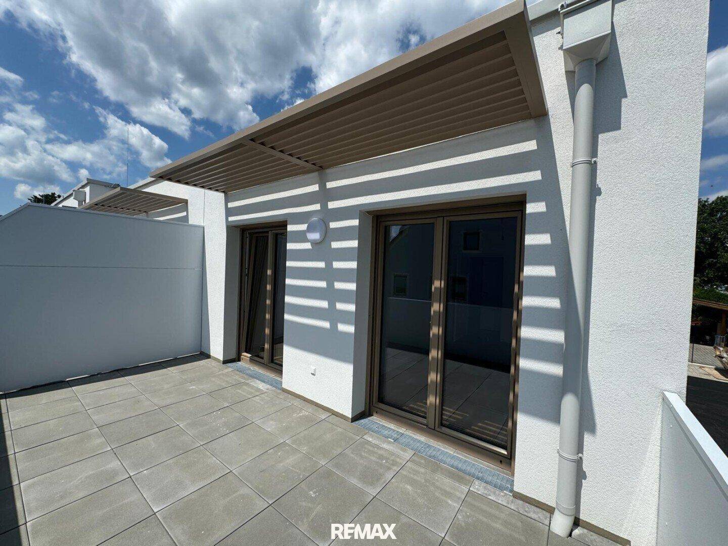 Sonniger Balkon mit Fliesenboden und einer modernen Pergola, ideal für entspannte Stunden im Freien.