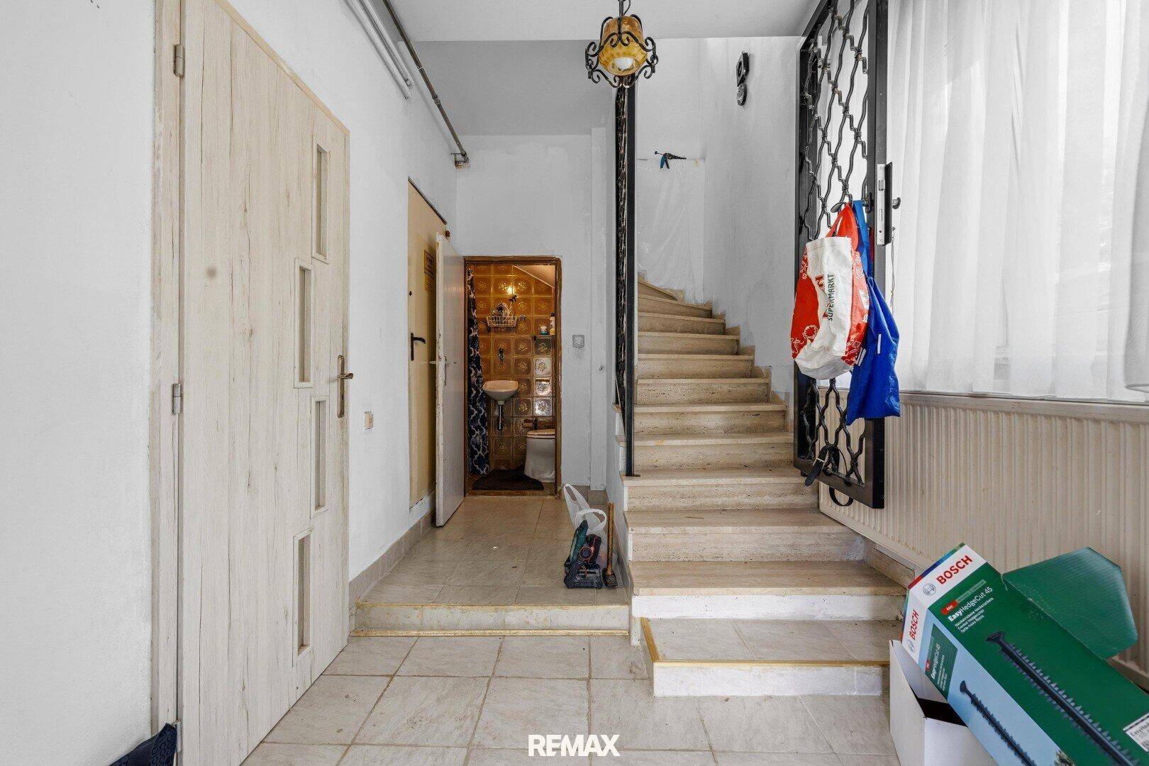 Eingangsbereich mit Treppe, gefliestem Boden und Zugang zu weiteren Räumen im Haus.