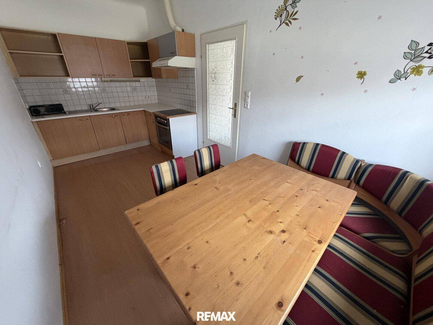 Gemütliche Wohnküche mit Holzschränken, Essbereich und Fensterblick.