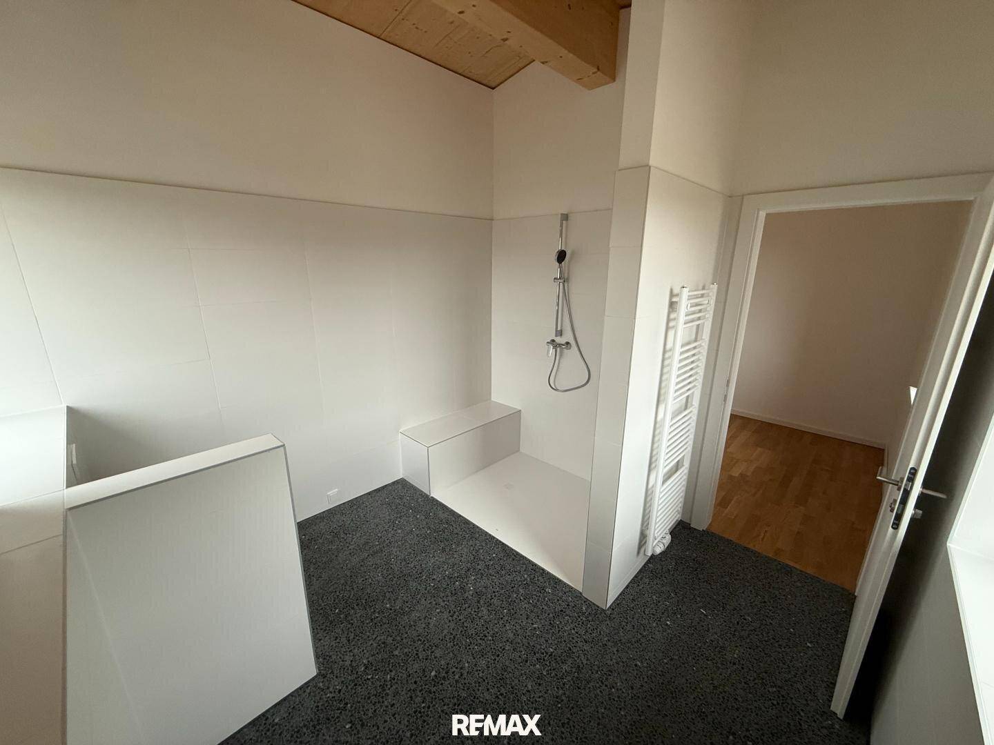 Modernes Badezimmer mit ebenerdiger Dusche und Handtuchheizkörper.