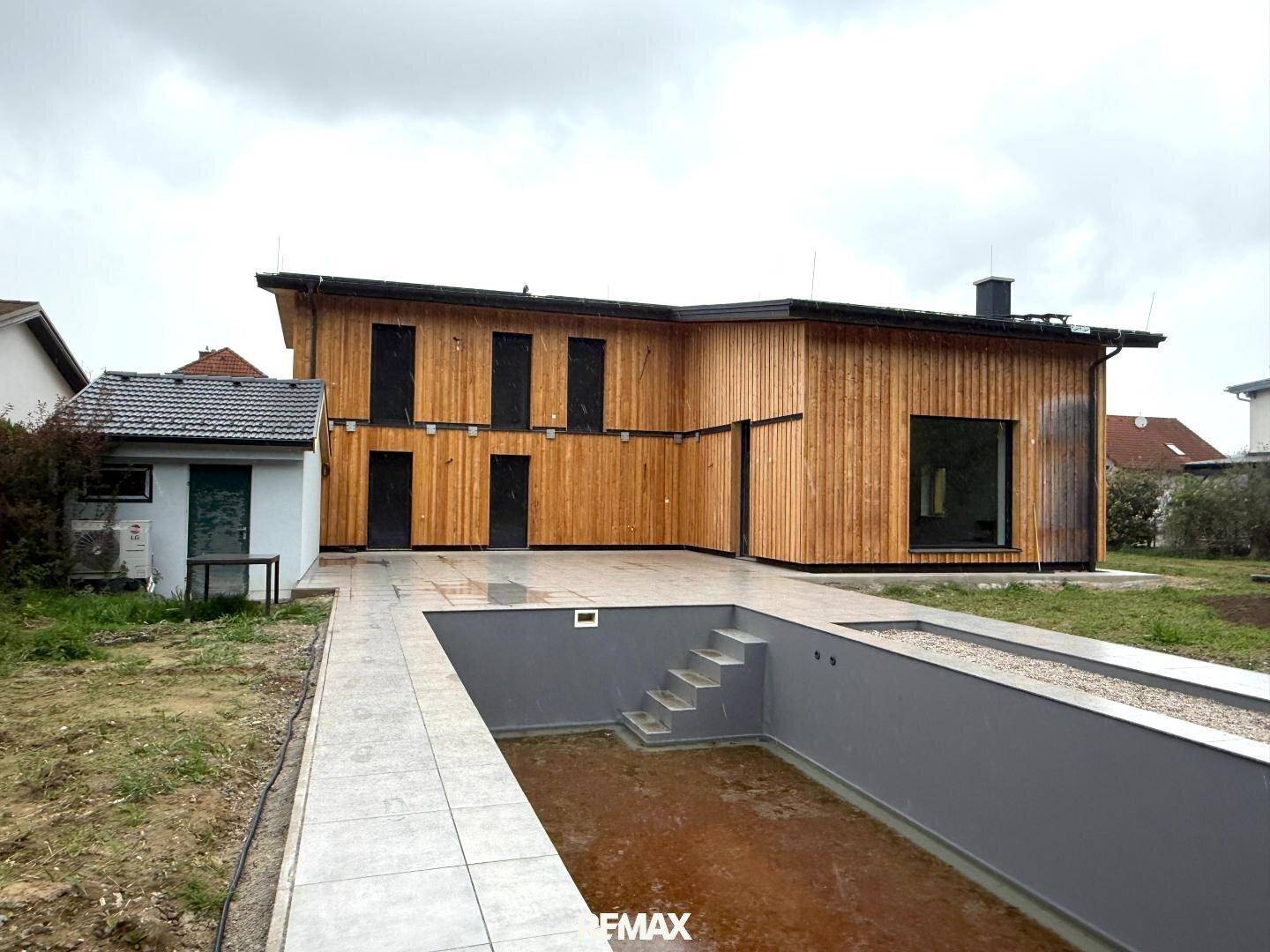 Rückseite des Hauses mit vorbereitetem Poolbereich und Terrasse im Bau.
