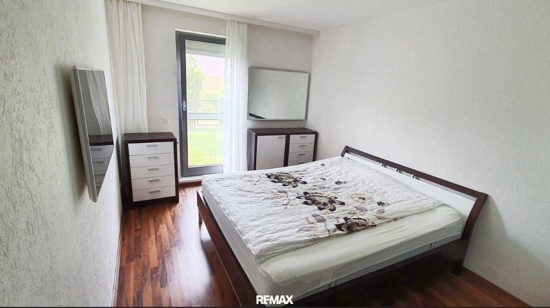 Schlafzimmer mit Holzboden, Doppelbett und direktem Zugang zu einem Außenbereich.