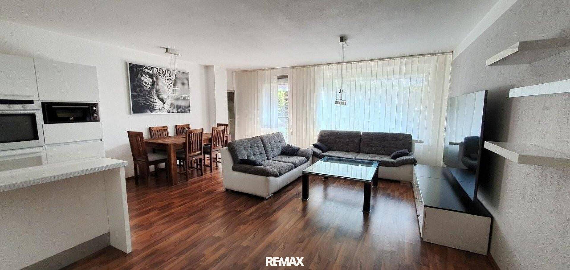 Heller offener Wohn- und Essbereich mit Holzboden und moderner Einrichtung.