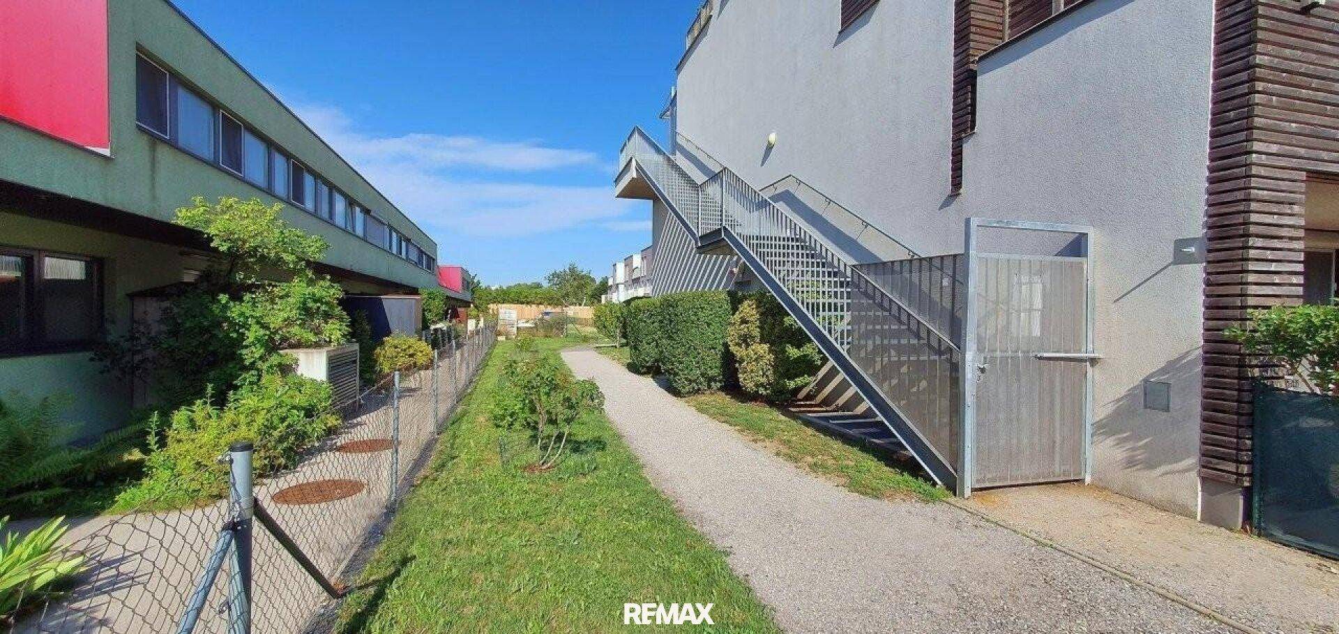 Außentreppe an der Gebäudeseite mit Zugang zu den oberen Etagen und einem Weg.