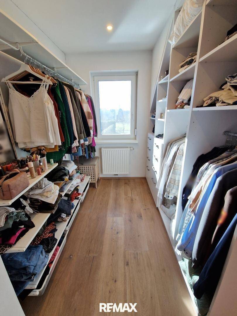 Geräumiger begehbarer Kleiderschrank mit viel Stauraum und Fenster für Tageslicht.