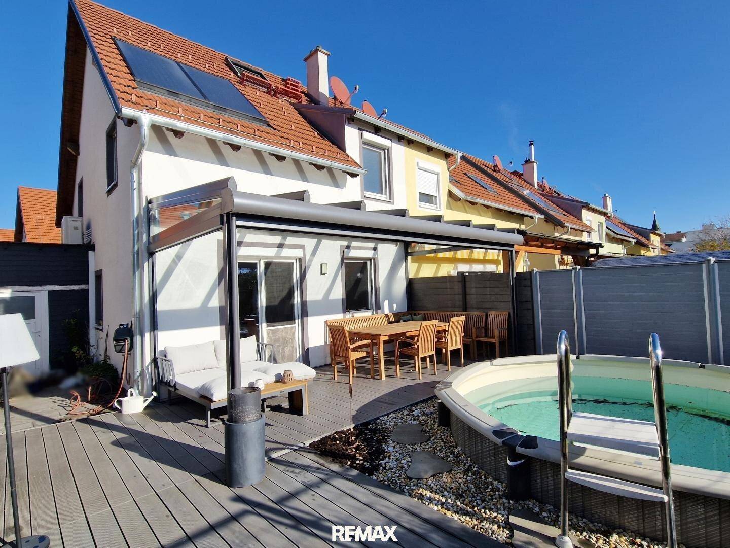 Außenansicht des Hauses mit überdachter Terrasse, Whirlpool und Solaranlage auf dem Dach.