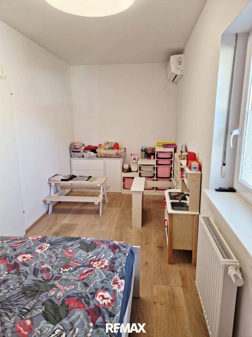 Helles Kinderzimmer mit Spielbereich, Holzboden und Klimaanlage, ideal für kleine Bewohner.
