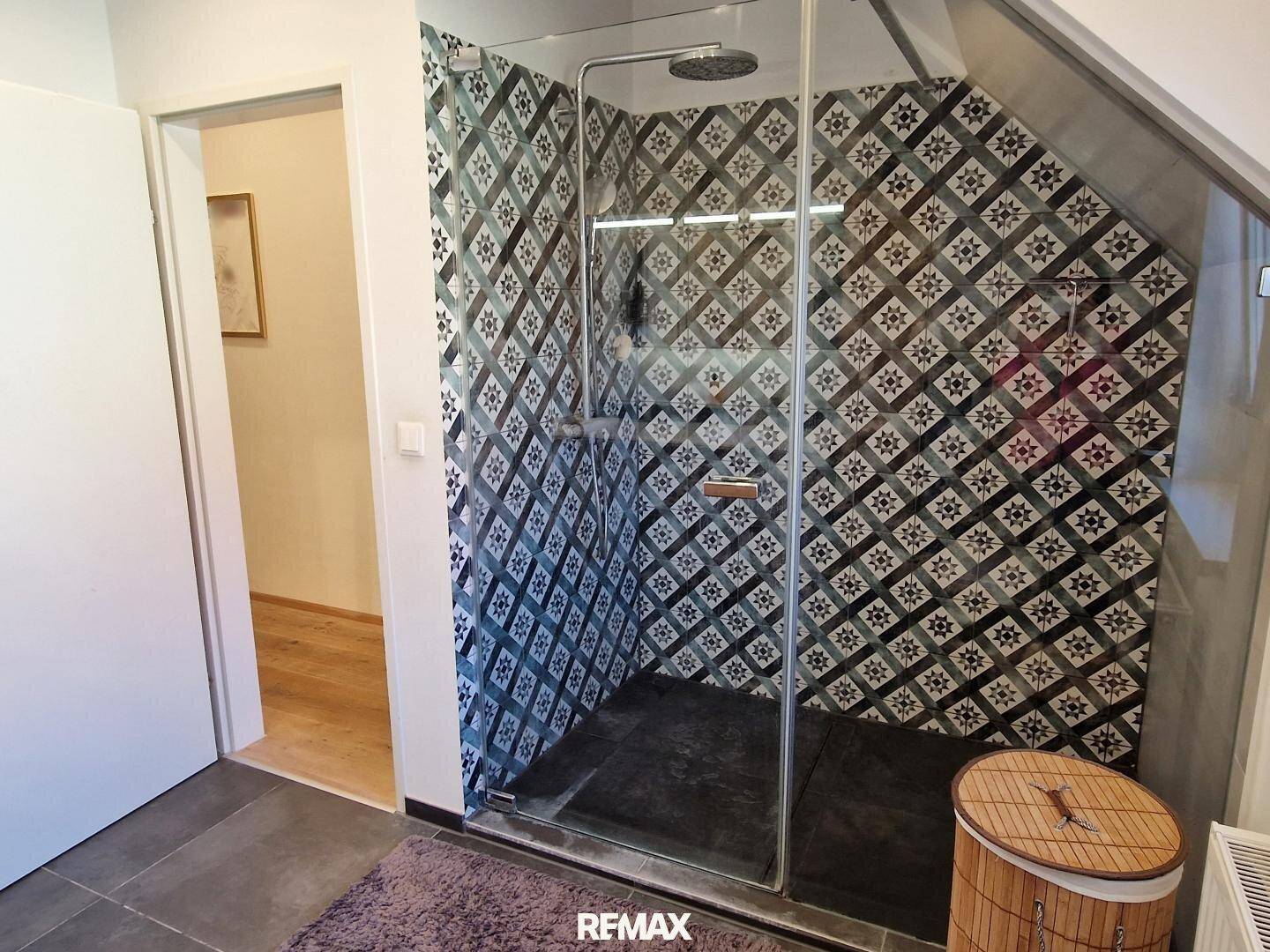 Geräumige begehbare Dusche mit modernen Fliesen und Glasabtrennung im Badezimmer.