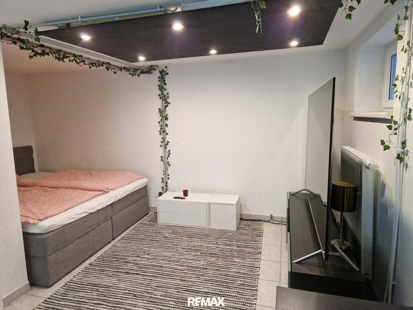 Gemütliches Zimmer im Untergeschoss mit Bett, Teppich und indirekter Deckenbeleuchtung.