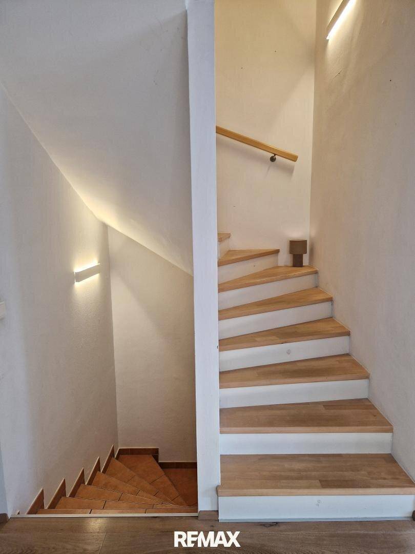 Moderne Holztreppe mit indirekter Beleuchtung, die die verschiedenen Etagen verbindet.