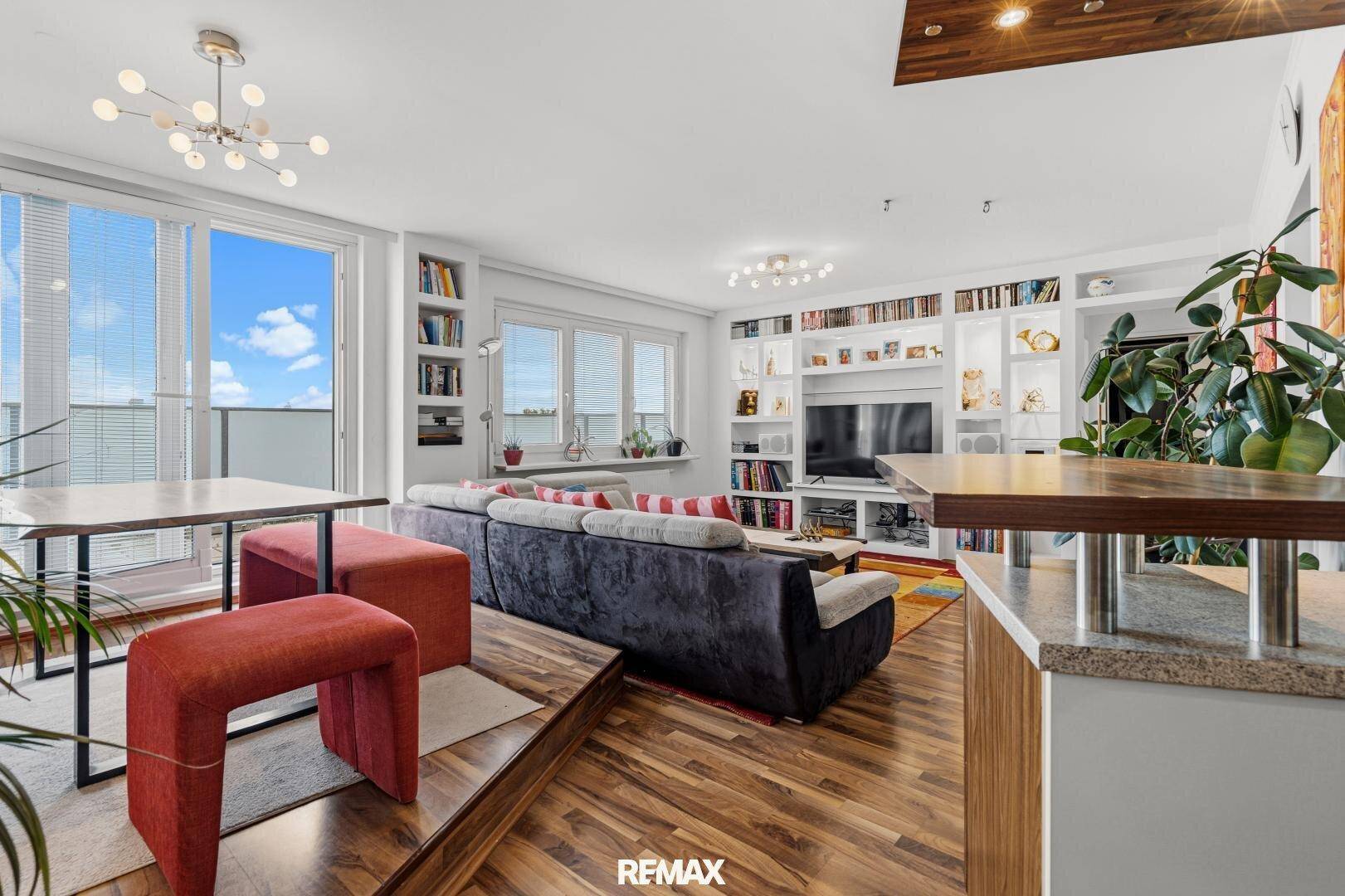 Helles Wohn- und Esszimmer mit Holzboden, eingebauten Regalen und Zugang zum Balkon.
