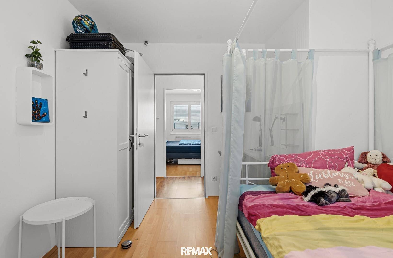 Schlafzimmer mit Himmelbett und Blick in einen weiteren Raum, hell und offen.