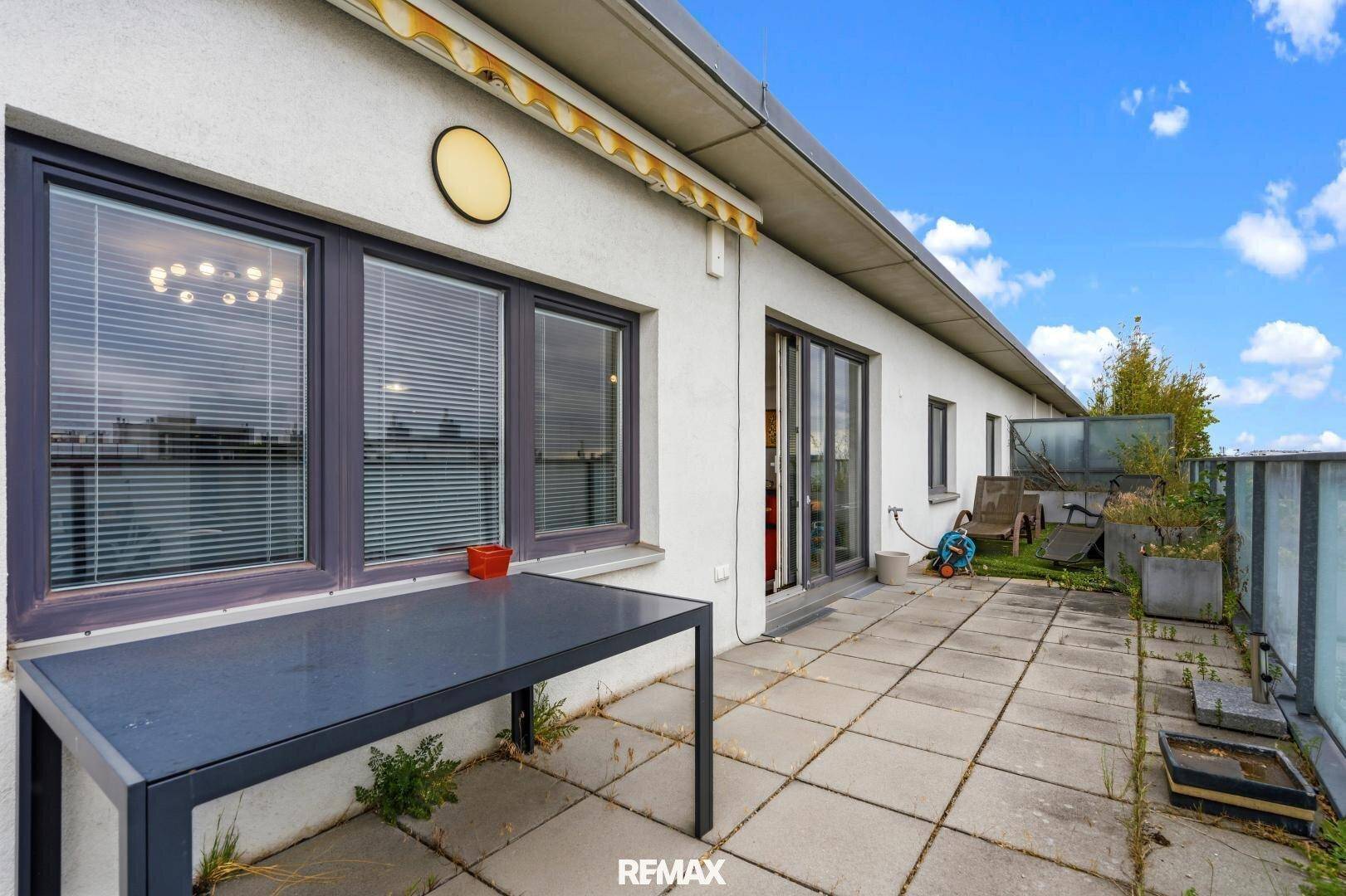 Geräumige Terrasse mit Steinplatten und einem Tisch, bietet Platz im Freien.