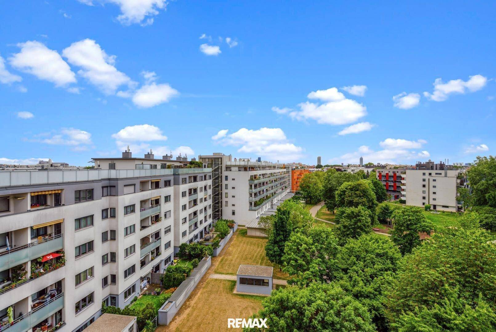 Weitläufige Wohnanlage mit viel Grünfläche und modernen Gebäuden unter blauem Himmel.