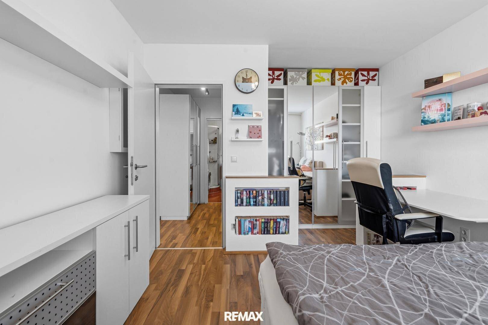 Schlafzimmer mit integrierten Schränken und Blick in den Flur, praktisch eingerichtet.