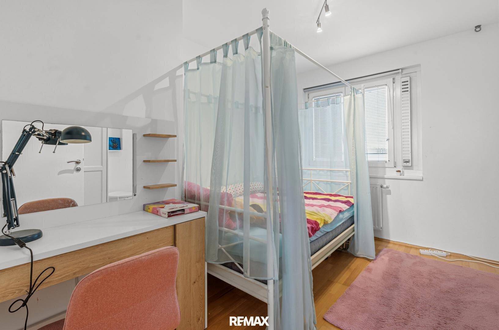 Kinderzimmer mit Himmelbett und Schreibtisch, hell und freundlich gestaltet.