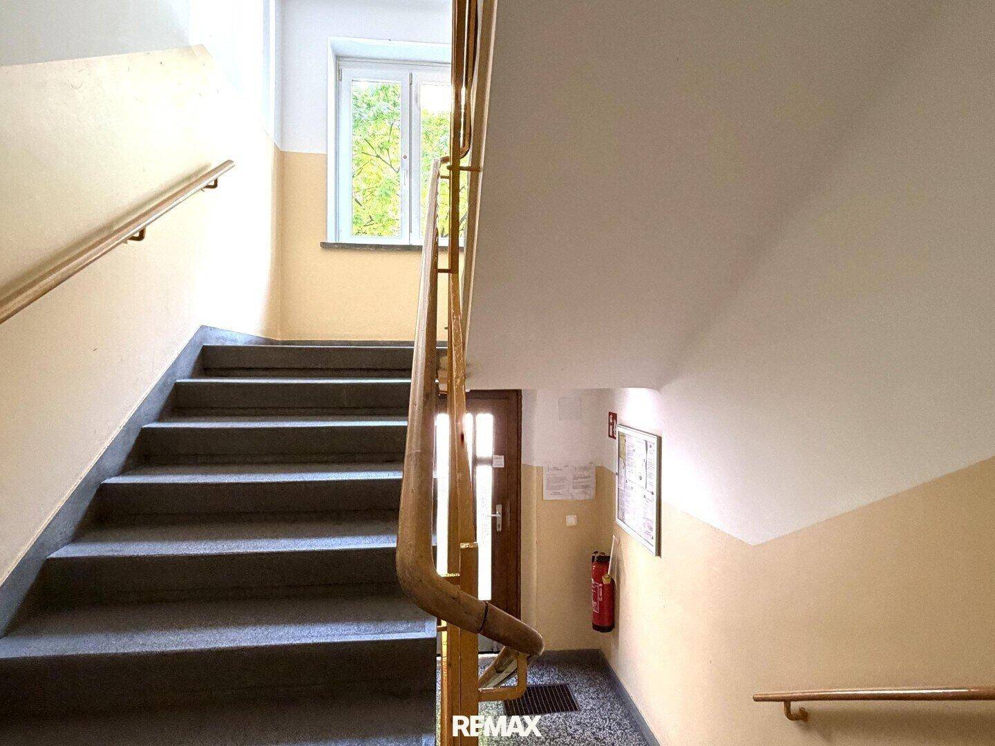 Treppenhaus mit Holzgeländer und Fenstern, das die verschiedenen Etagen verbindet.