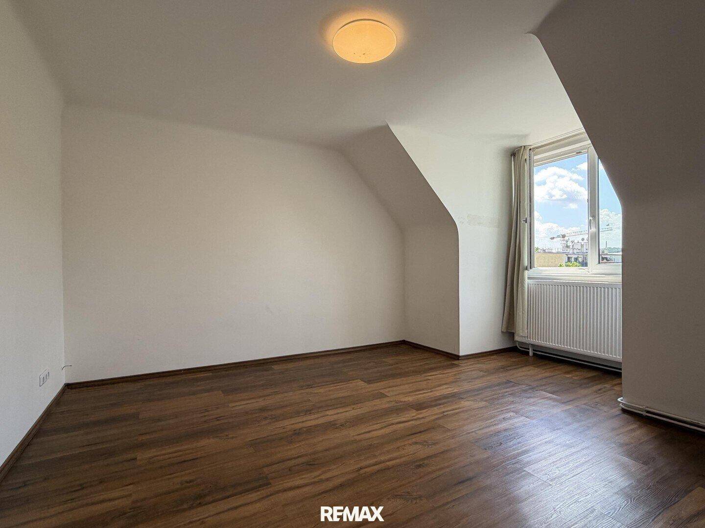 Geräumiges Zimmer mit Dachschrägen und Laminatboden, ideal als Schlaf- oder Arbeitszimmer.
