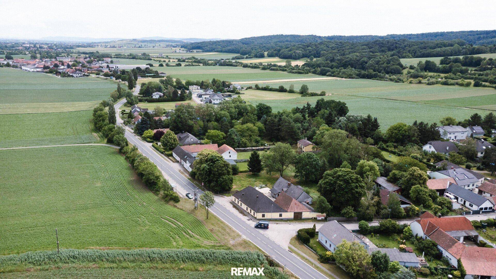 Panoramische Luftaufnahme des Anwesens eingebettet in eine weite ländliche Landschaft mit Feldern und Wäldern.