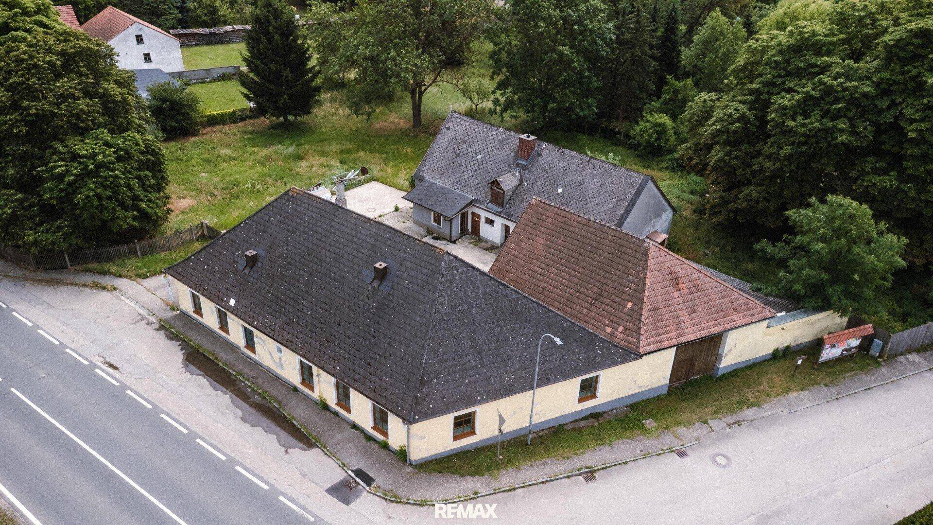 Nahaufnahme der Hauptgebäude des Anwesens aus der Vogelperspektive mit umliegender Grünfläche.