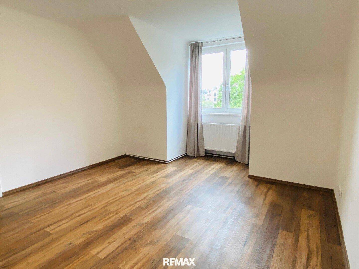 Helles Zimmer mit Dachschrägen und Laminatboden, gut geeignet als Kinder- oder Gästezimmer.