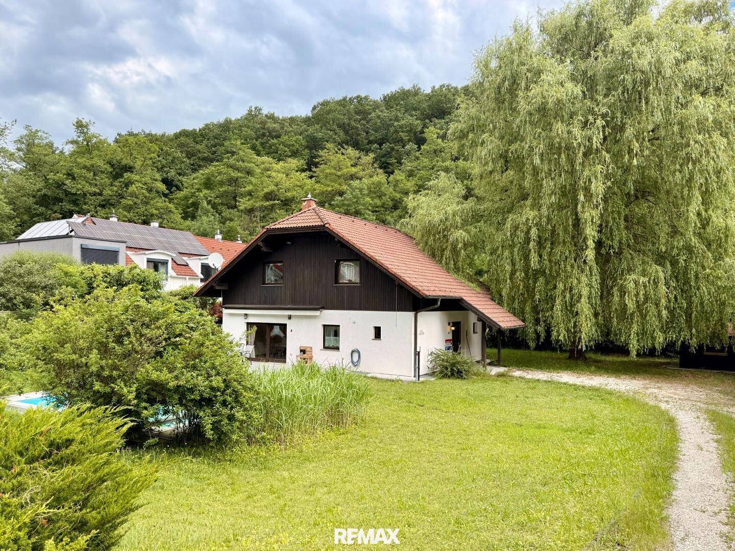 Freistehendes Haus mit Satteldach, umgeben von viel Grün und Bäumen in ländlicher Umgebung.