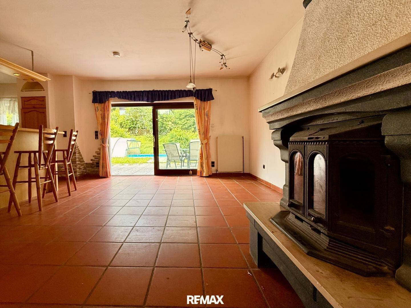 Geräumiges Wohnzimmer mit Kaminofen, Terrakottaboden und direktem Zugang zum Gartenbereich.
