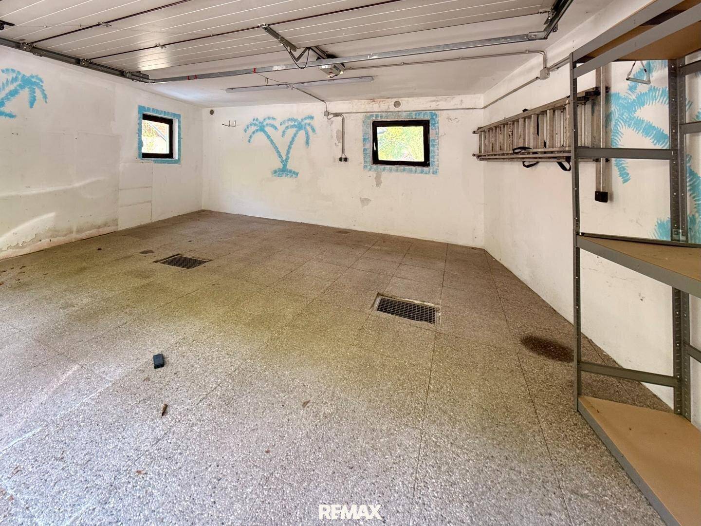 Geräumige Garage oder Abstellraum mit Betonboden und kleinen Fenstern, ideal für Lagerung.