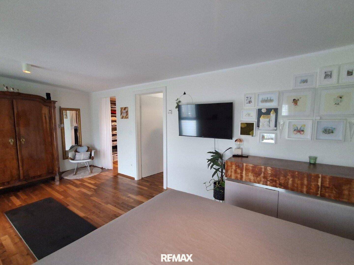 Geräumiges Schlafzimmer mit Holzboden, großem Kleiderschrank und Zugang zum Ankleidezimmer.