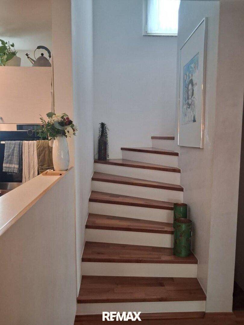 Helle Holztreppe führt in die obere Etage, mit dekorativen Elementen an der Wand.