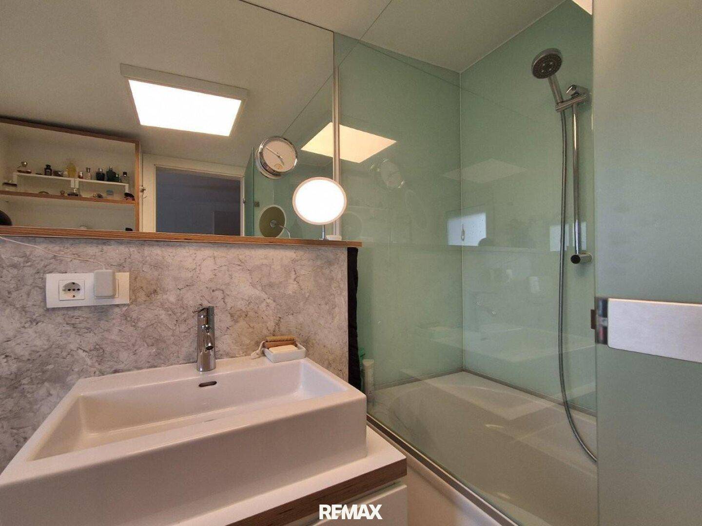 Helles Badezimmer mit modernem Waschtisch und einer geräumigen Glasdusche.