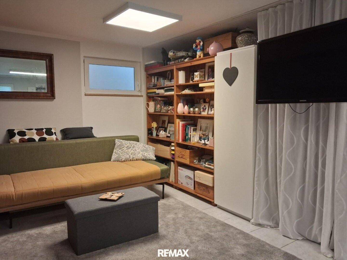 Ausgebauter Kellerraum als gemütlicher Wohnbereich mit Sofa und Bücherregal.