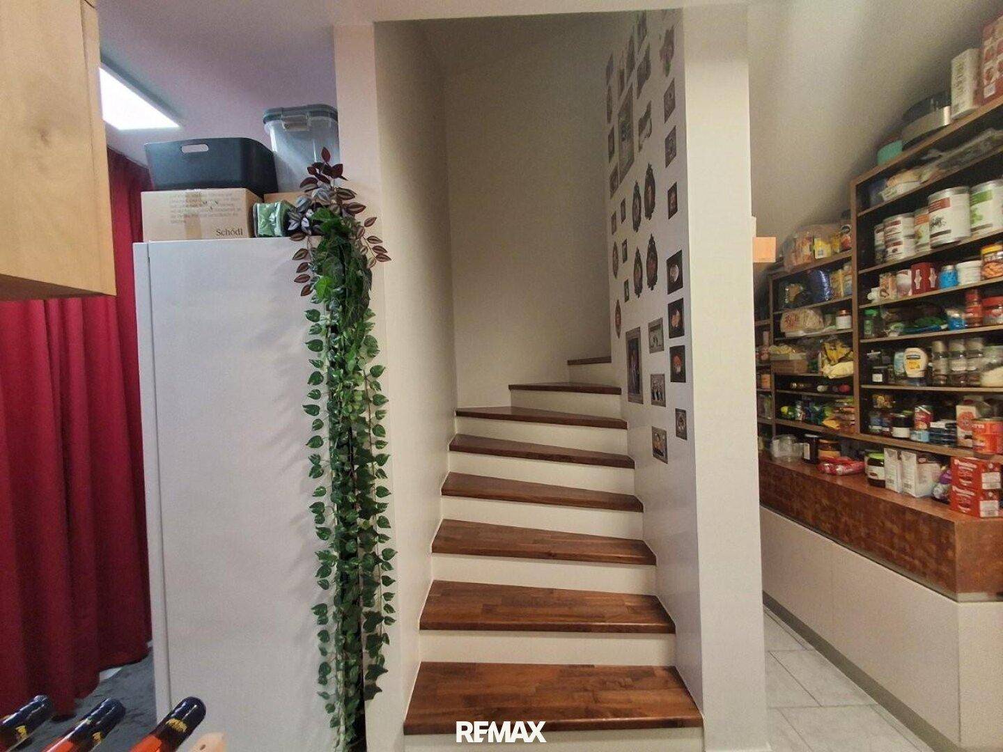 Praktische Speisekammer mit Regalen voller Vorräte, neben einer Holztreppe.