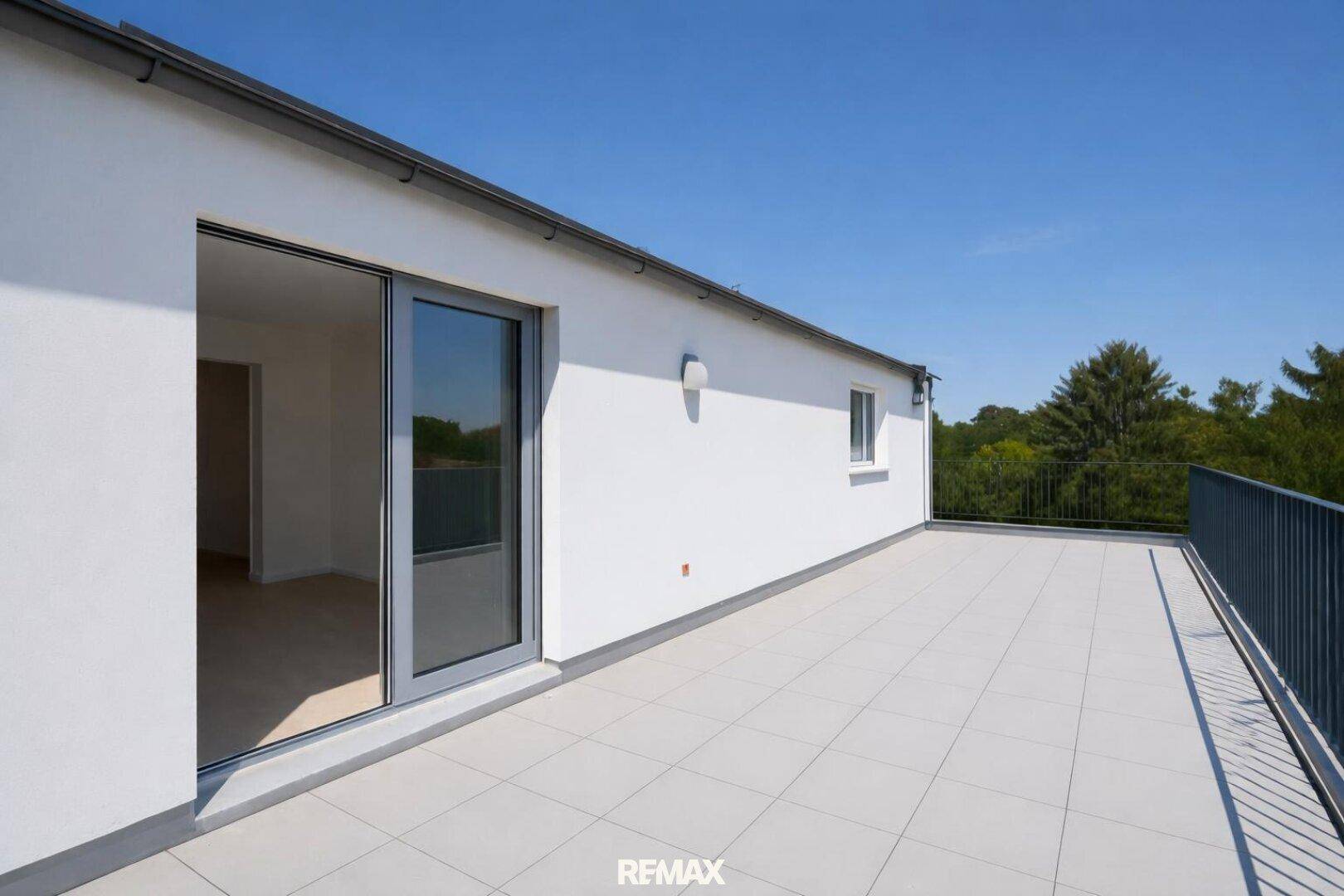 Große, leere Dachterrasse mit hellen Fliesen und weitem Blick in die Umgebung.