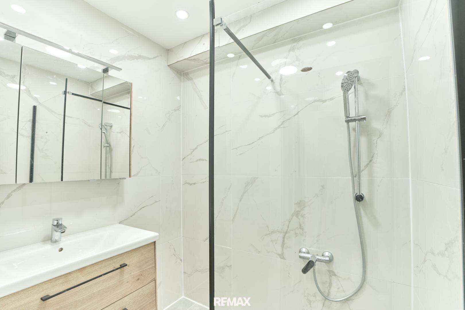 Modernes Badezimmer mit begehbarer Dusche, Marmorfliesen und einem Einzelwaschbecken mit Unterschrank.