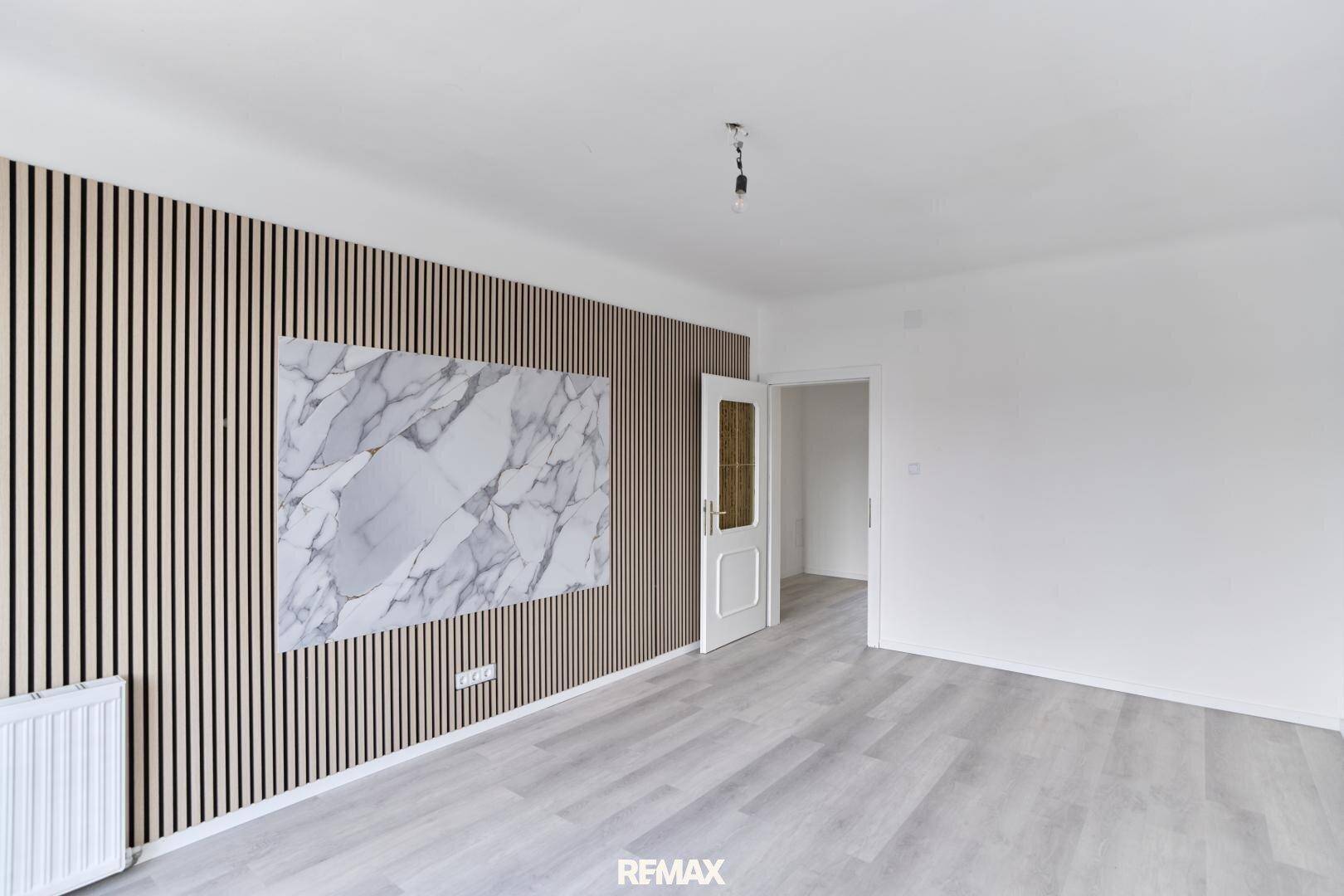 Geräumiges Zimmer mit dekorativer Holzlattung und Marmor-Akzentwand, bereit zur Einrichtung.