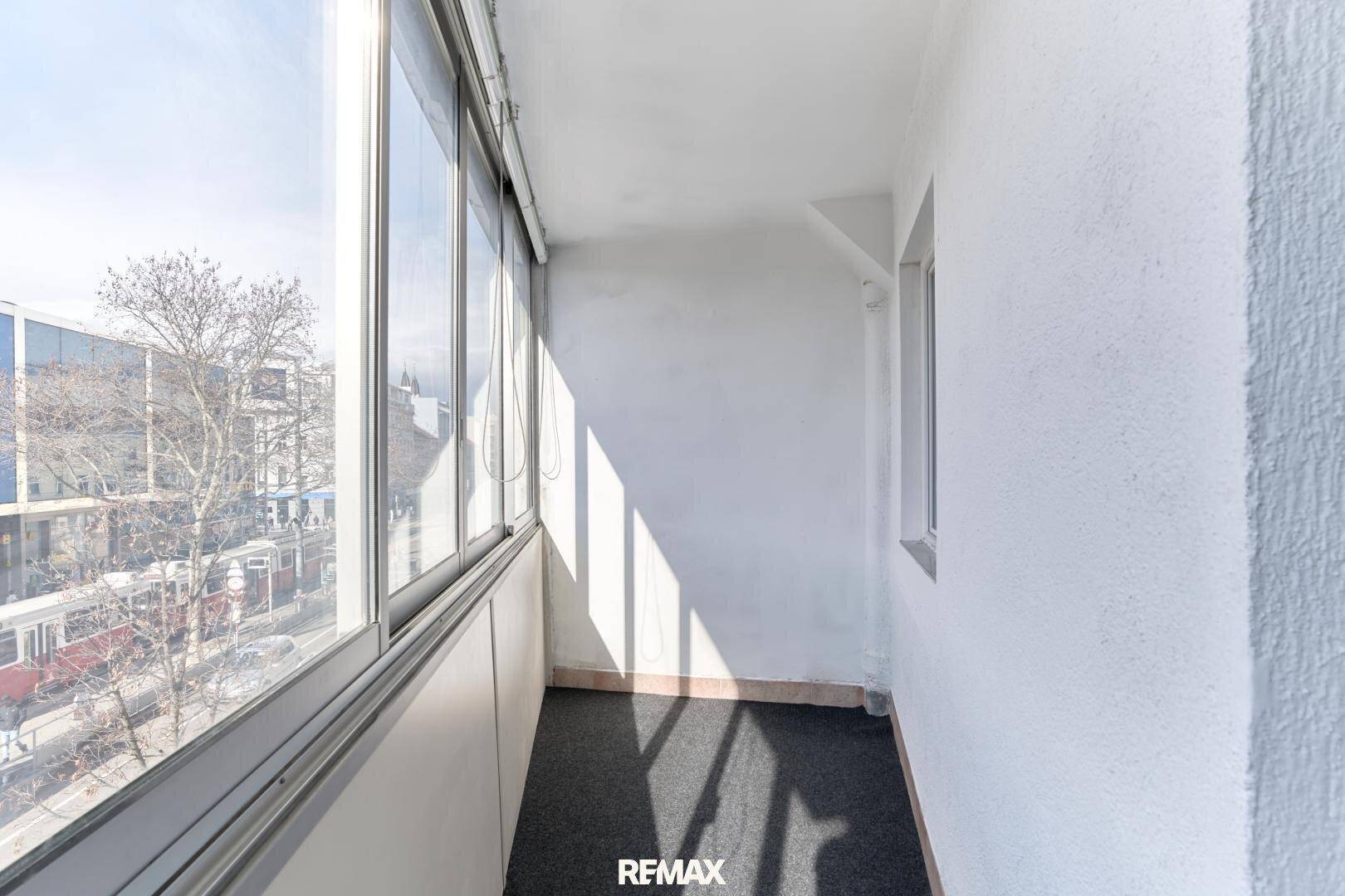 Heller, verglaster Balkon mit Blick auf die Stadt und viel natürlichem Tageslicht.