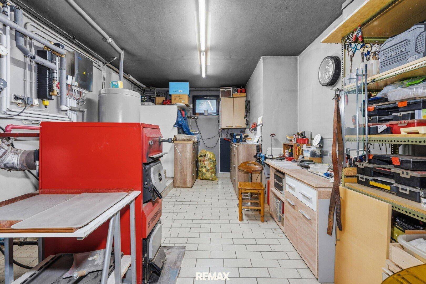 Geräumiger Heizungsraum mit großem Kessel, Werkbank und Lagerregalen, ideal für Hobby und Technik.